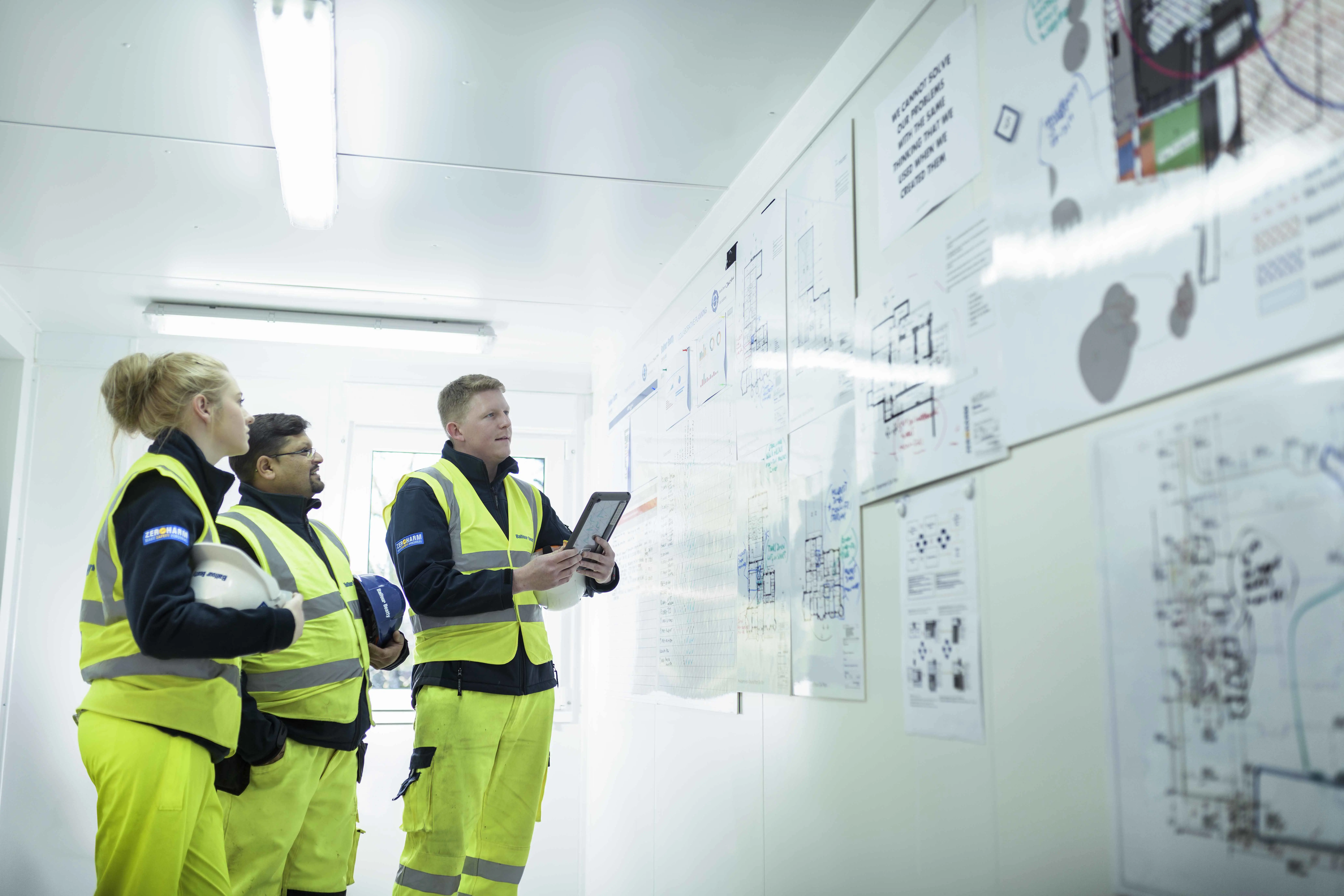Three site workers assessing briefing board